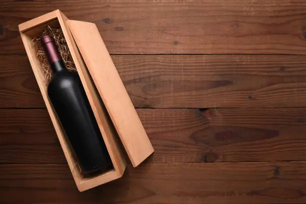 Cabernet Wine Box: A single Bottle of red wine in its wooden case on a dark wood table with copy space.