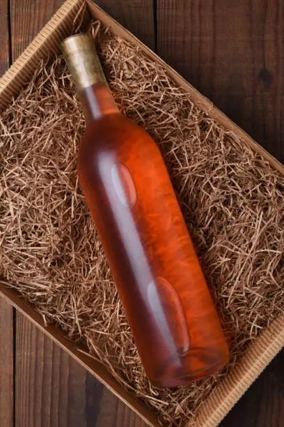 Blush Wine Bottle in Packing Straw: High angle shot of a single bottle in a cardboard box with straw packing.