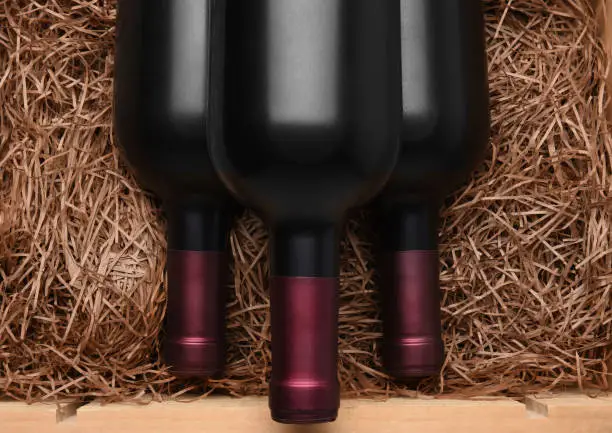 Three Cabernet Bottles:  Three Bottles of red wine in a wood case with packing straw.