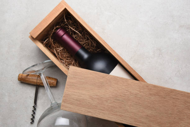 Cabernet in a wood box partially covered by its lid Cabernet Wine Box: A Red wine bottle in a wood box partially covered by its lid with a glass and corkscrew. maroon photos stock pictures, royalty-free photos & images