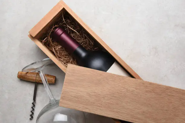 Cabernet Wine Box: A Red wine bottle in a wood box partially covered by its lid with a glass and corkscrew.