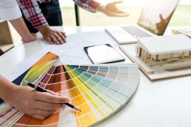 istock Two young women interior design or graphic designer working on project of architecture drawing with work tools and color swatches, colour chart in digital tablet at workplace 950844394