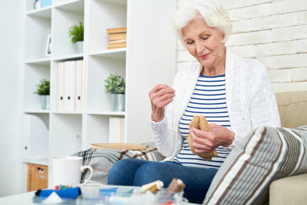 istock Smiling granny sewing toy at home 950847136