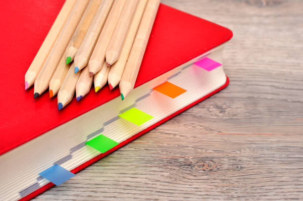 istock Red diary notebook and colored pencils on the desk wood texture. 950850380
