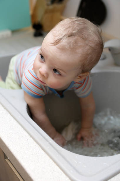 istock Toddler sitting in the kitchen sink 950851574