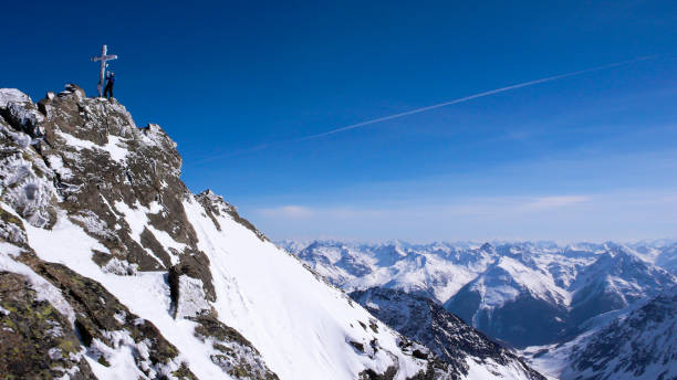мужской лыжник бэккантри на вершине креста высокогорного пика в прекрасный зимний день - mountain switzerland scuol mountain peak стоковые фото и изображения