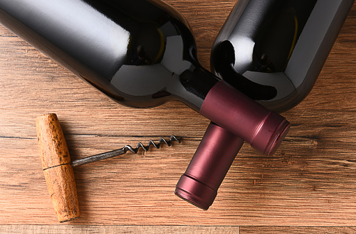 Top view of two wine bottles with their necks crossed and and old fashioned cork screw.