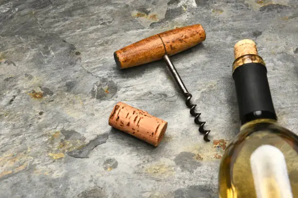 Top view of a wine bottle and cork screw on a slate surface.
