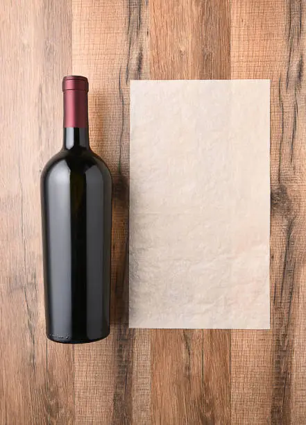 Top view of a wine bottle next to a blank sheet of paper. Wine list concept.