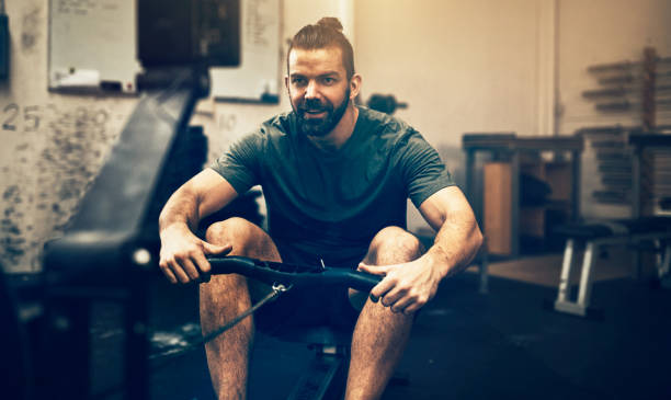 istock Smiling young man working out on a gym rowing machine 950865364