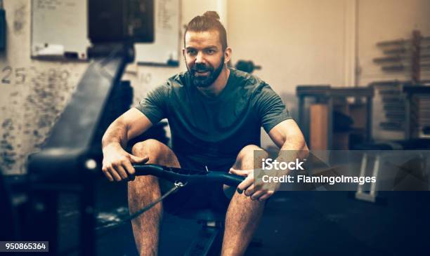 Smiling Young Man Working Out On A Gym Rowing Machine Stock Photo - Download Image Now