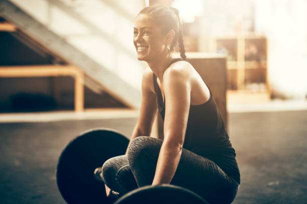 ジムでウェイトを解除する準備をして若い女性を笑顔 - gym women inside of exercising ストックフォトと画像