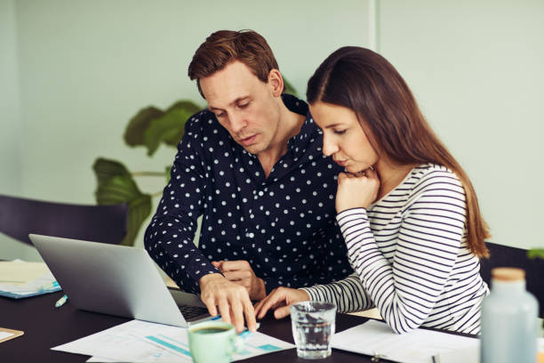 istock Two office colleagues sitting at a desk discussing paperwork together 950874978