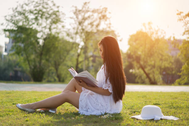 istock Young women reading book in park 950875974