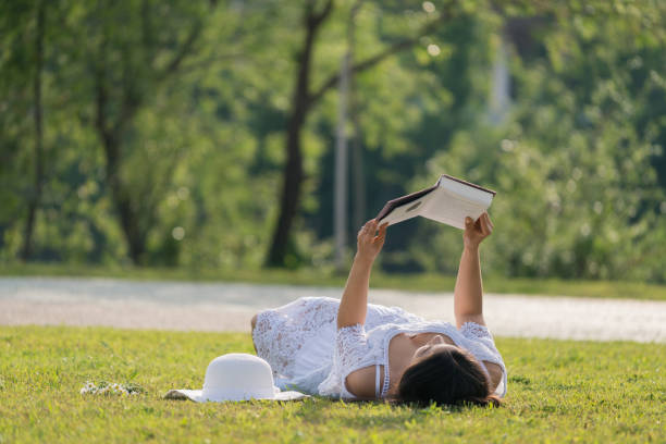 istock Young women relaxing and reading book in park 950879912