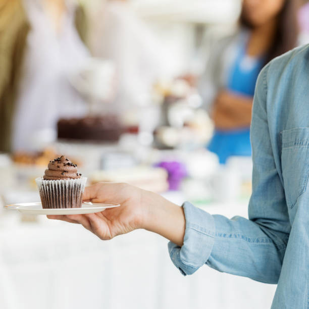 istock Woman holds cupcake during bake sale 950886928