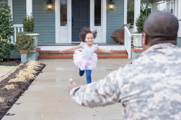 Adorable little girl runs to the open arms of her father who has just returned home from serving overseas in the military.