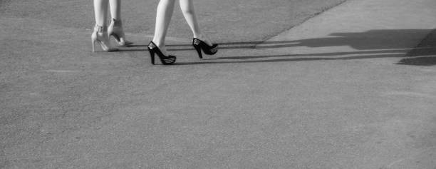 istock Two modern girls on high heels stand on sunny asphalt 950888346