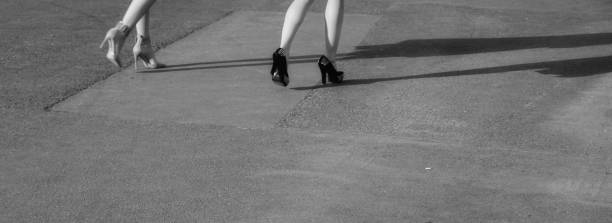 istock Two modern girls on high heels stand on sunny asphalt 950890504