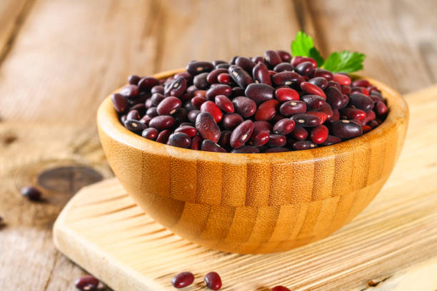 istock Red raw beans with greens on a wooden table. 950891726
