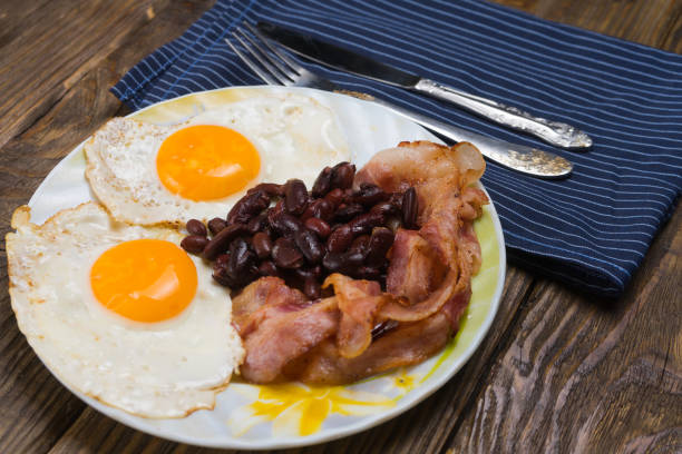 istock Plate with scrambled eggs, bacon and beans on a wooden rustic table. 950899610