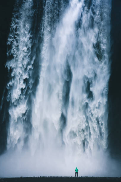 excursionista de pie delante de la gigantesca cascada de skogafoss en islandia - large waterfall fotografías e imágenes de stock