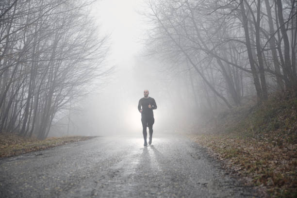 istock one runner jogging, outdoors mist fog, mysterious forest. 950914448