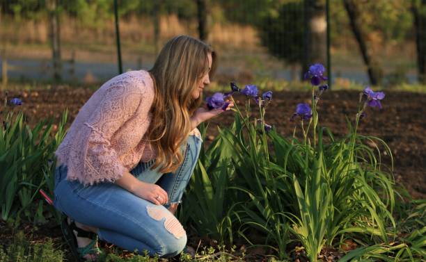 美しい長い髪ブロンドの十代女の子の臭いがする紫色のアイリス-春の日に花 - iris single flower flower outdoors ストックフォトと画像