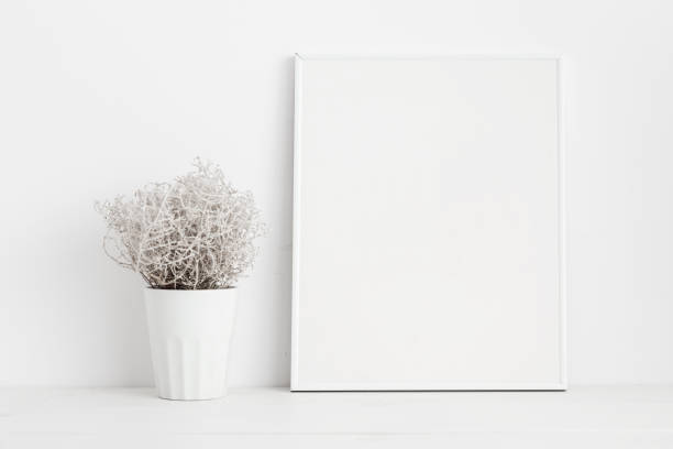 istock Mock up white frame and plant on bookshelf or desk. White colors. 950917842