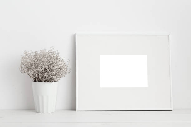 istock Mock up white frame and plant on bookshelf or desk. White colors. 950917862