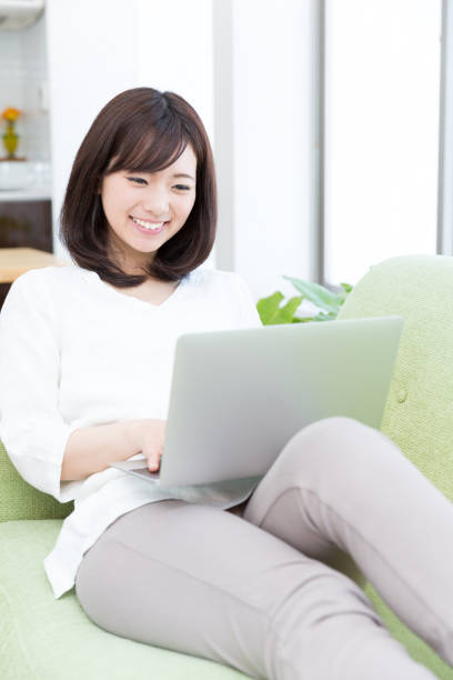 istock attractive asian woman using laptop on sofa 950918246