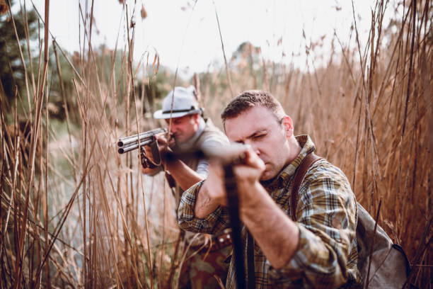 grupa myśliwych ukrytych na bagnach i przygotowujących się do polowania - hunting two people camouflage rifle zdjęcia i obrazy z banku zdjęć