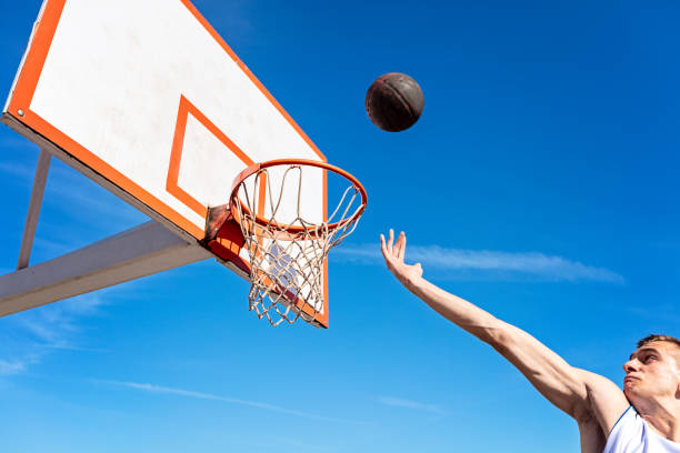 istock Slam Dunk. Side view of young basketball player making slam dunk 950922770