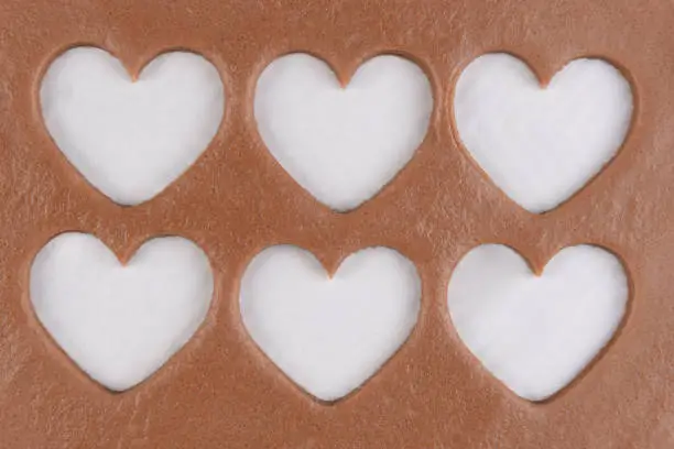 Valentines Day Baking: Six heart shapes cut out of a sheet of chocolate cookie dough.