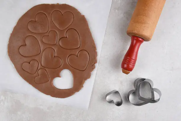 Valentines Day Baking: Top view of chocolate cookie dough with hearts shapes and rolling pin.
