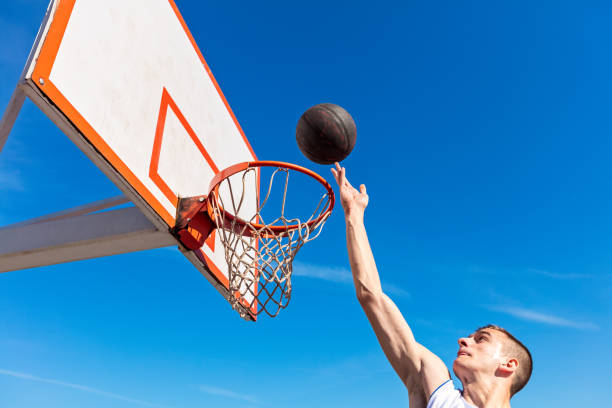 istock Slam Dunk. Side view of young basketball player making slam dunk 950923820