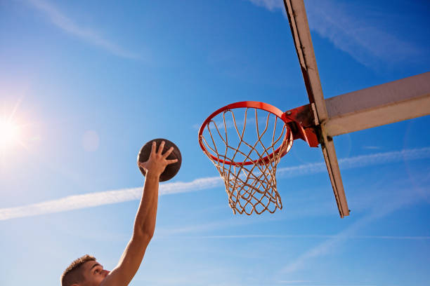istock Slam Dunk. Side view of young basketball player making slam dunk 950925982