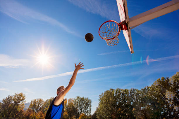 istock Slam Dunk. Side view of young basketball player making slam dunk 950926862