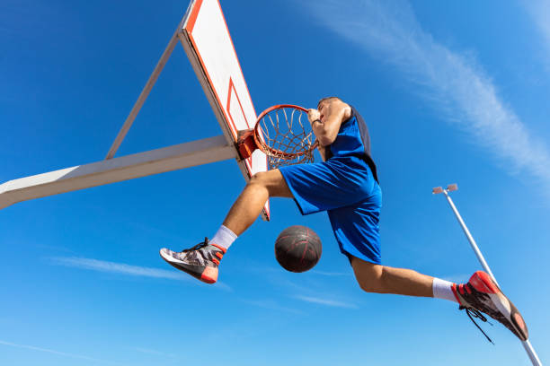 istock Slam Dunk. Side view of young basketball player making slam dunk 950928126