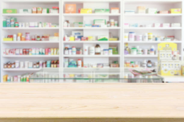 аптечная аптека счетчик стол с размытием абстрактных backbround с медициной и медицинским продуктом на полках - аптека стоковые фото и изображения