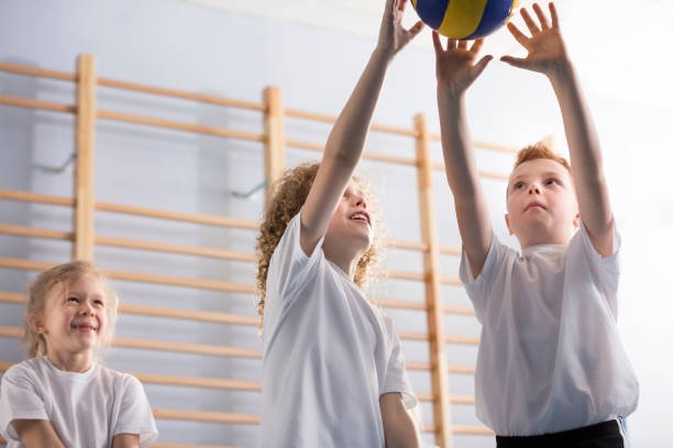 Happy boys playing volleyball Low angle of happy boys playing volleyball during sports activities at school low body fat stock pictures, royalty-free photos & images