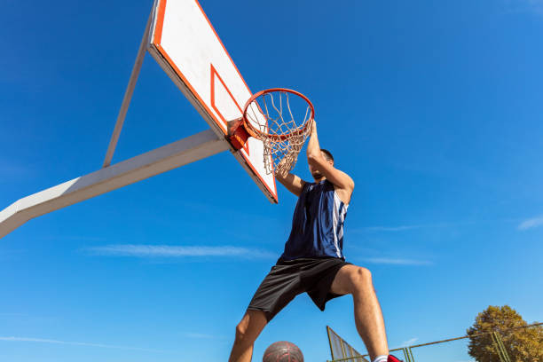 istock Slam Dunk. Side view of young basketball player making slam dunk 950930808