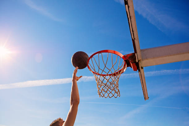 istock Slam Dunk. Side view of young basketball player making slam dunk 950932602