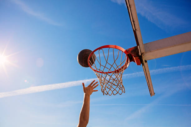 istock Slam Dunk. Side view of young basketball player making slam dunk 950932938