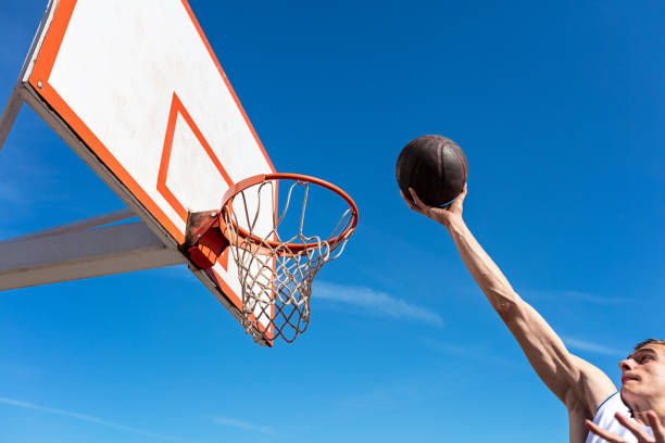 istock Slam Dunk. Side view of young basketball player making slam dunk 950933818