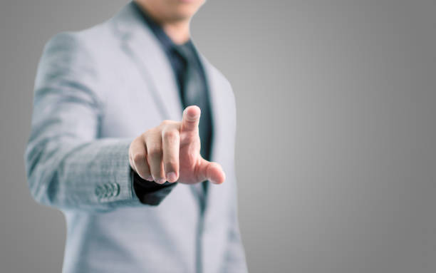 Businessman in gray suit is pointing his finger to touch the screen concept Businessman in gray suit is pointing his finger to touch the screen concept with gray background clicking screen stock pictures, royalty-free photos & images