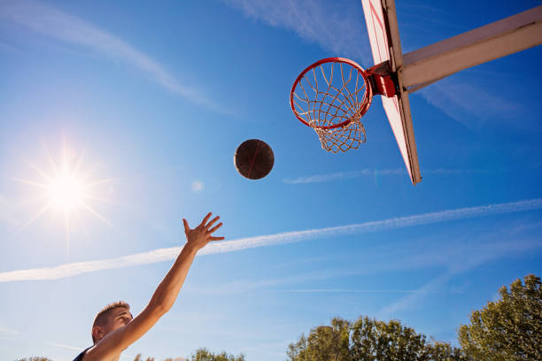 istock Slam Dunk. Side view of young basketball player making slam dunk 950938422