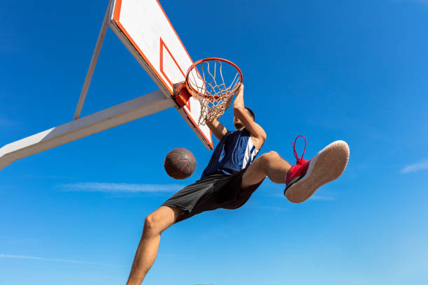 istock Slam Dunk. Side view of young basketball player making slam dunk 950939156