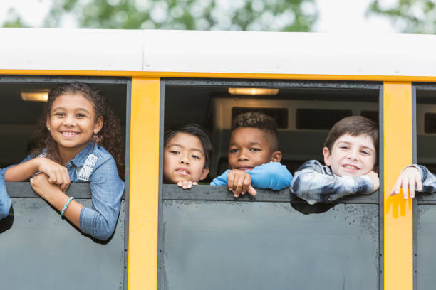 istock Elementary school children looking out window of bus 950953598