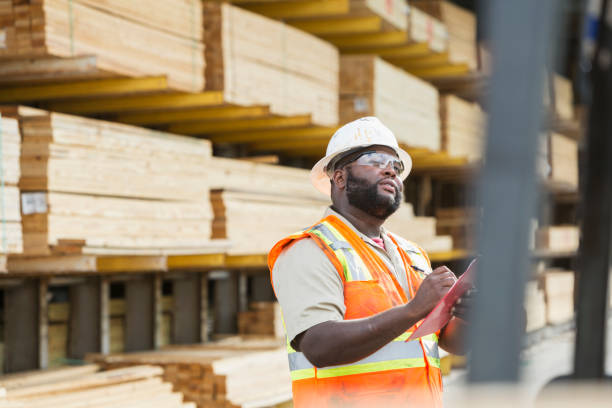 afrikanisch-amerikanischer mann arbeitet in einem holzlager inventar - minority african ethnicity business hardhat stock-fotos und bilder